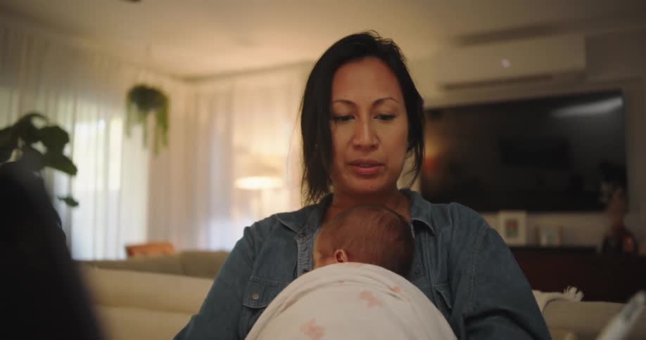 A mother holding her baby in her lap and sitting taking notes with a pen in a notebook