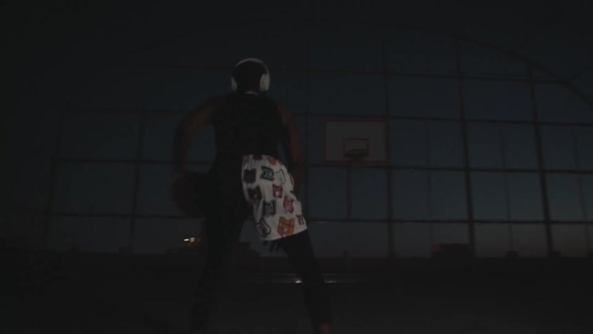 Man with headphones practicing basketball moves on a court