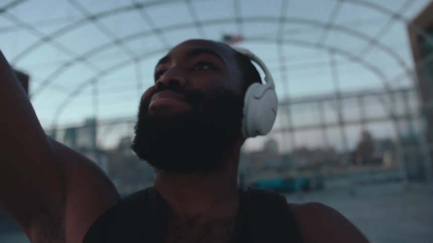 A man with headphones playing basketball on his own