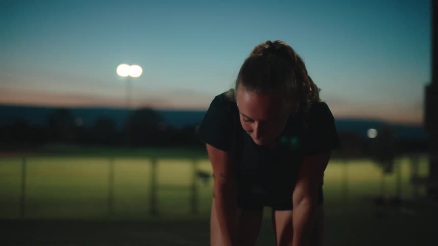 Woman with her hands on her legs on an athletics track tired