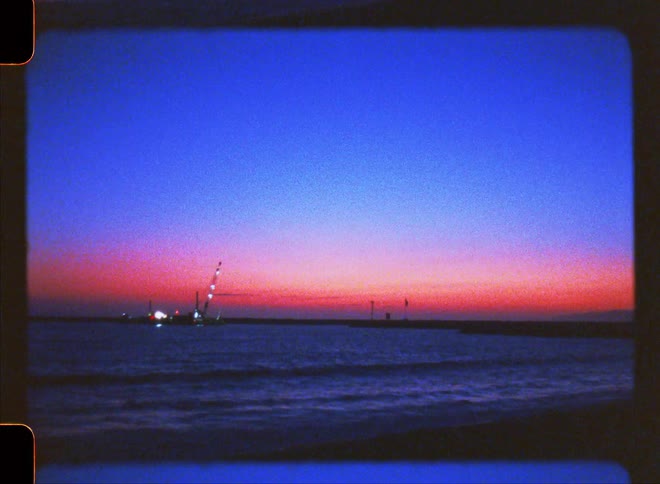 A woman dancing on the beach by the sea silhouetted against the red sky at sunset