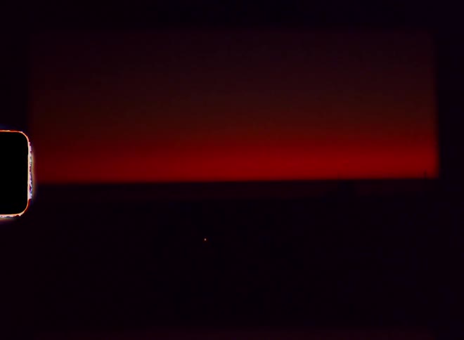 Lighthouse stands silhouetted against a red sky