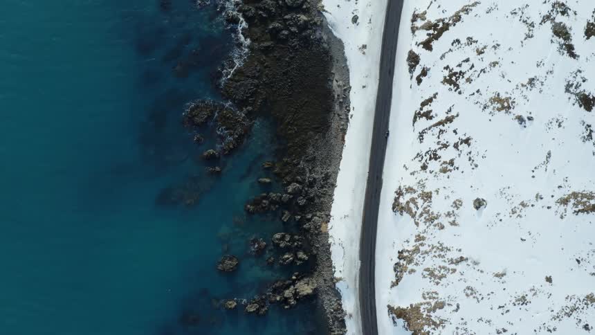 Aerial view of a coastline where the sea meets a snowy and rocky landmass