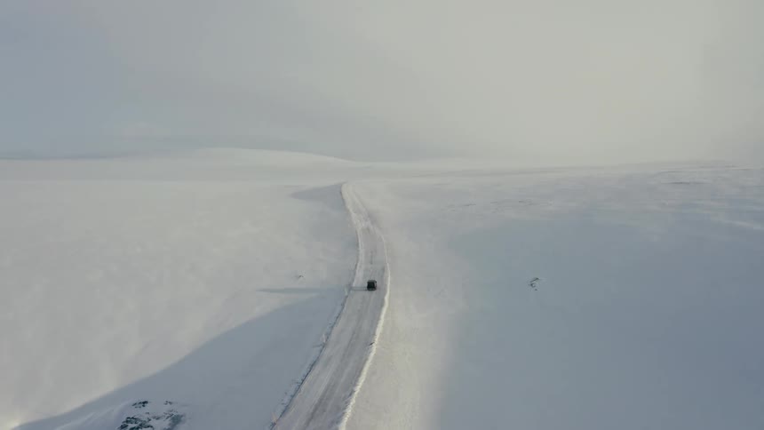 A vehicle drives on a snow covered road