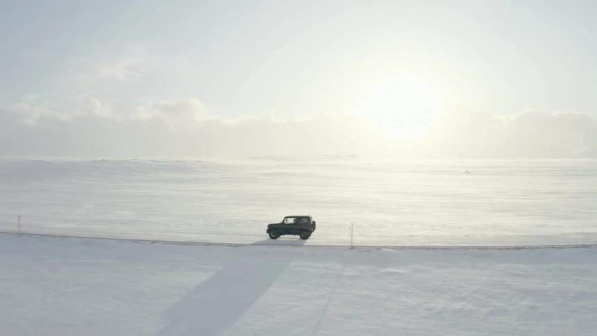 A vehicle drives across a snow covered road