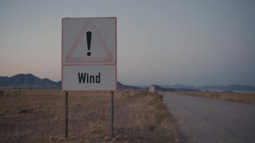 Attention sign on the side of a road in a natural environment with mountains on the horizon