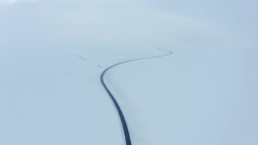 A huge asphalt street in a region covered in white snow on the sides