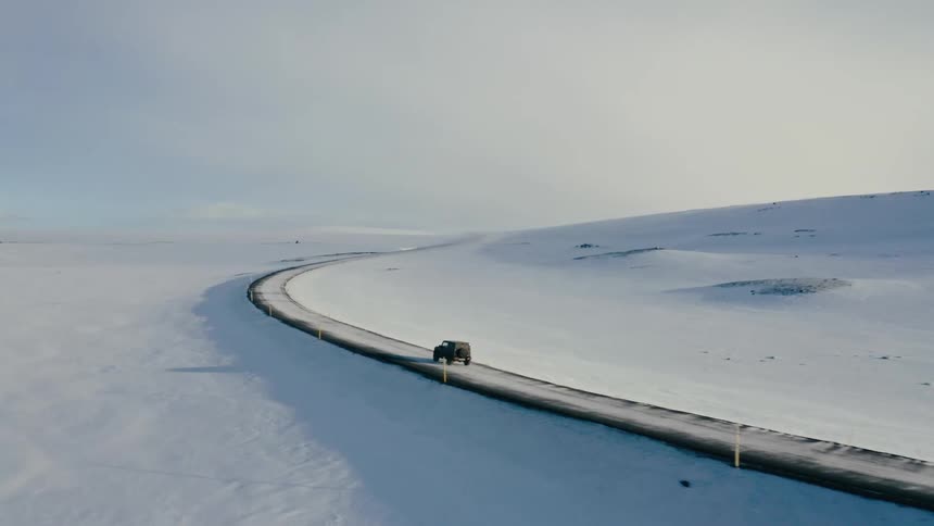 Black jeep traveling on a paved road with snowcovered sides in a natural environment