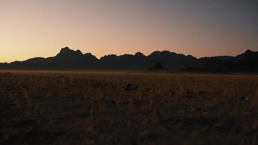 Mountains serve as a backdrop to a large grassy field