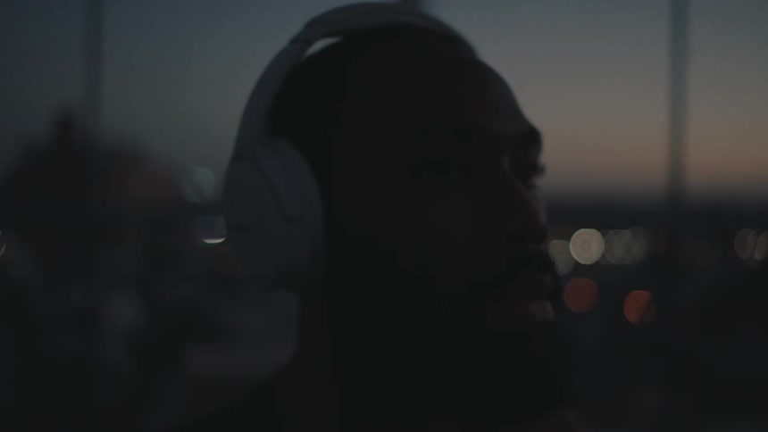 A bearded man has a white headset on his head and is shaking it