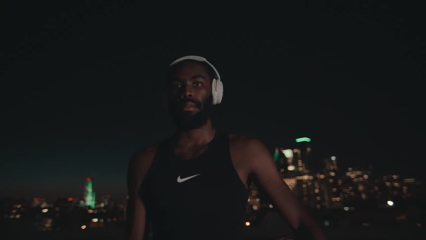 A black man holding a basketball outdoors at night