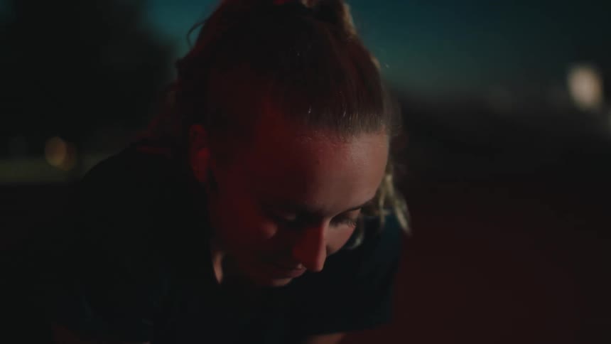 Portrait of a woman crouching on a running track at night