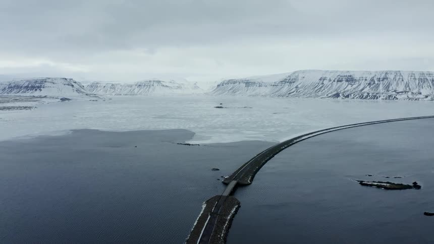A road runs past a mountainous shoreline