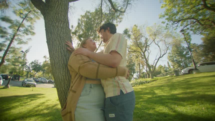 Romantic couple embracing in a garden next to a tree