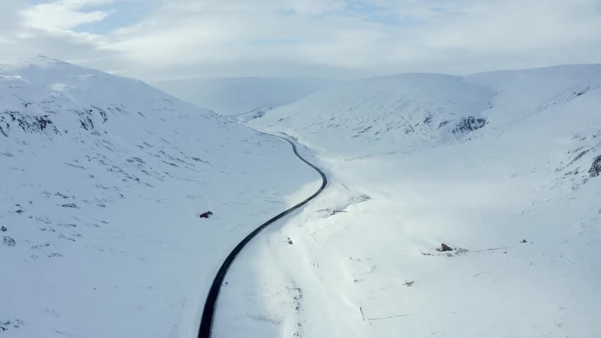 An asphalt road in a snowy region with snowcovered hills