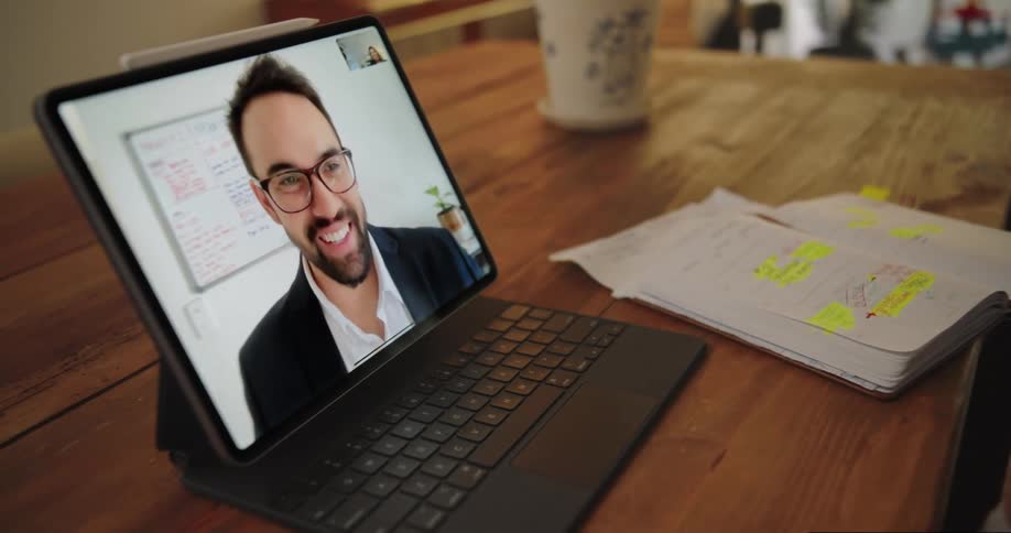 Man waves from screen during video call with person working from home