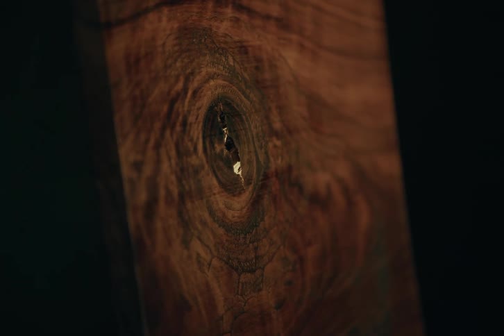 Piece of varnished wood with nodule in the upper left part on a black background