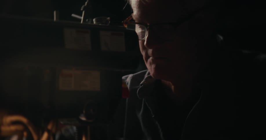 Portrait of a man working on a machine in an indoor room with low natural lighting