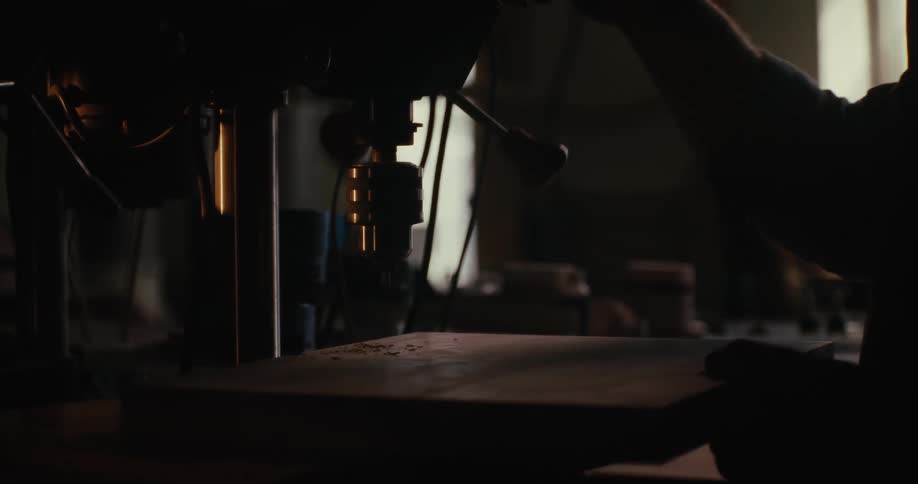 Woodworker uses jigsaw on board then dusts sawdust off the board