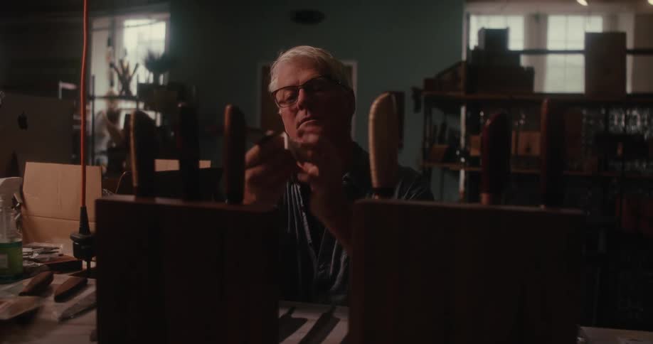 A blade smith polishes knives and places them on a wooden shelf