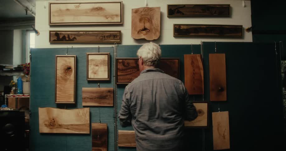 A man makes sure artwork is hanging properly