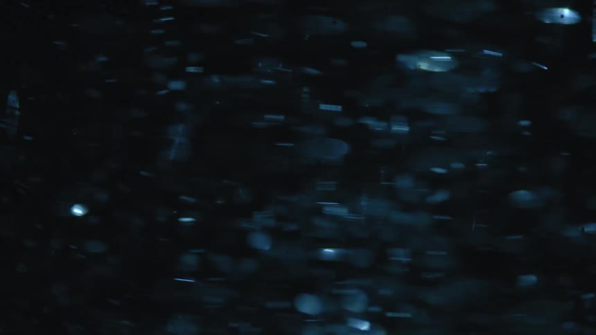 Disks swirl through dark area reflecting blue light while forming a column