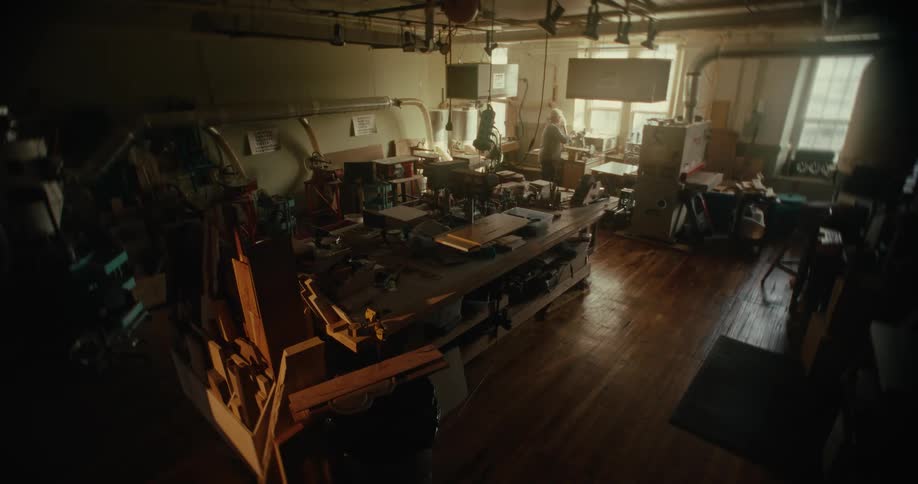 Male woodworker works in workshop as traffic passes windows