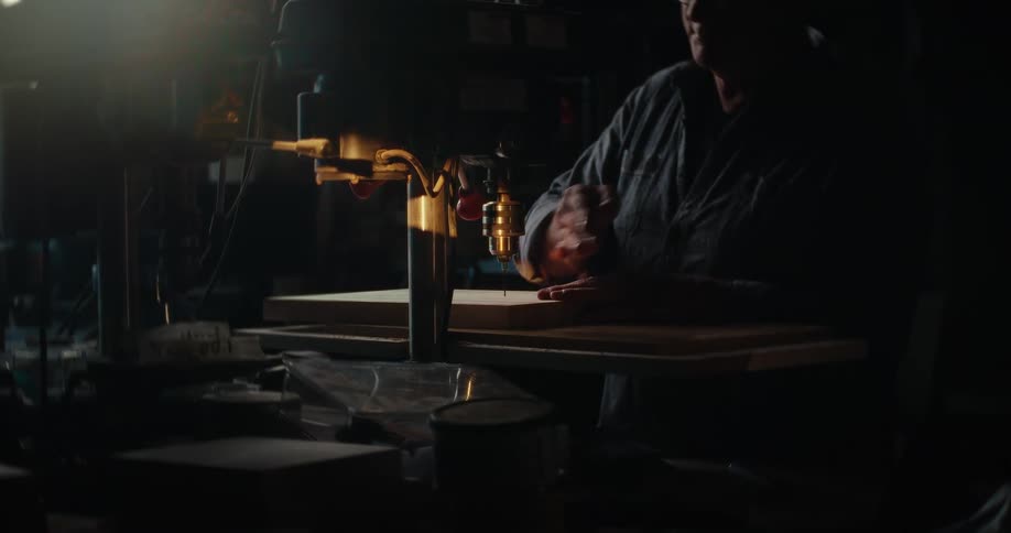 Man placing a piece of wood into a drilling machine