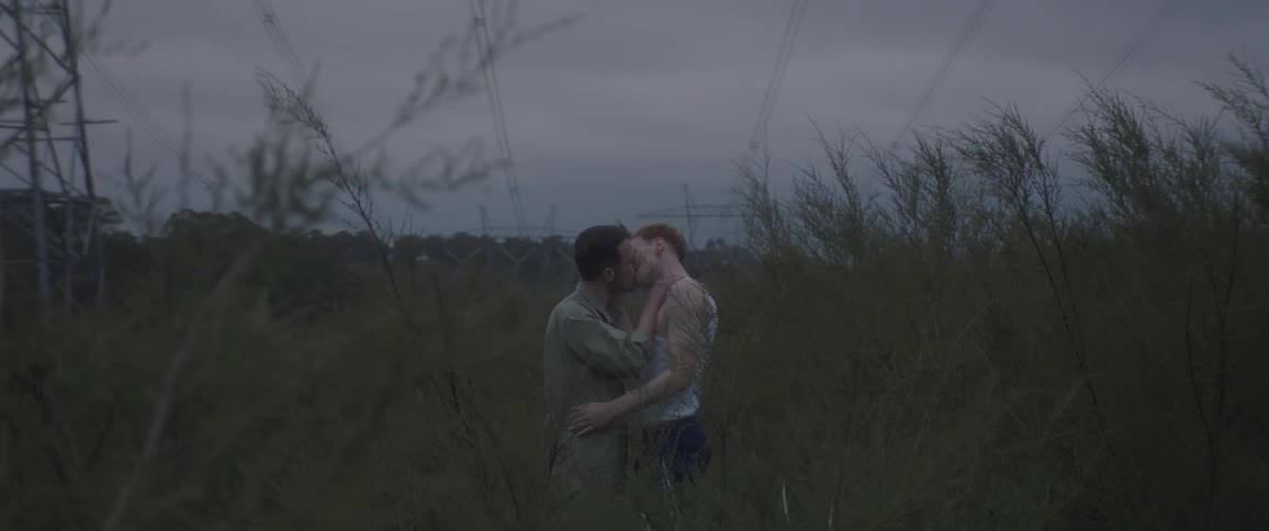 Couple of two men in a wooded field kissing