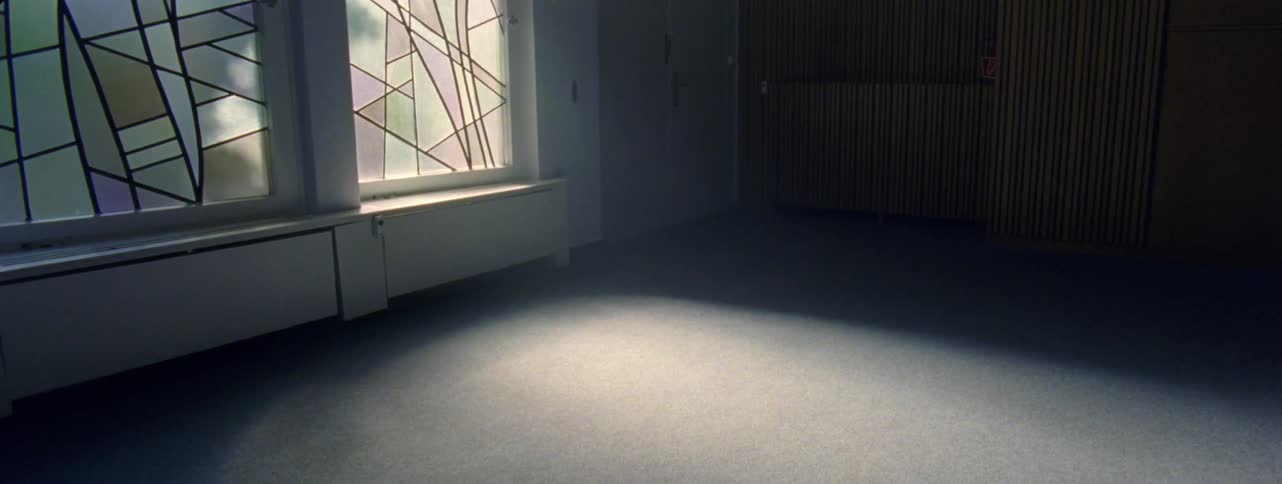 An empty room and a window with natural light that reflects on the floor of the room