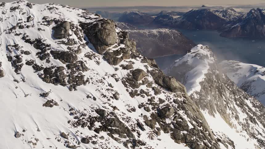 Aerial of a snowcovered mountain range next to a body of water