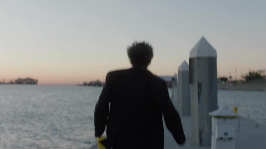 A man in a suit runs up to the end of a pier