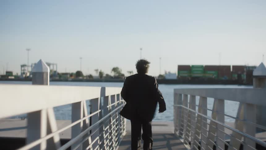 A man runs down a walkway towards a pier