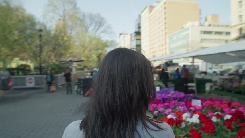 Back of a woman buying flowers on a market in the city