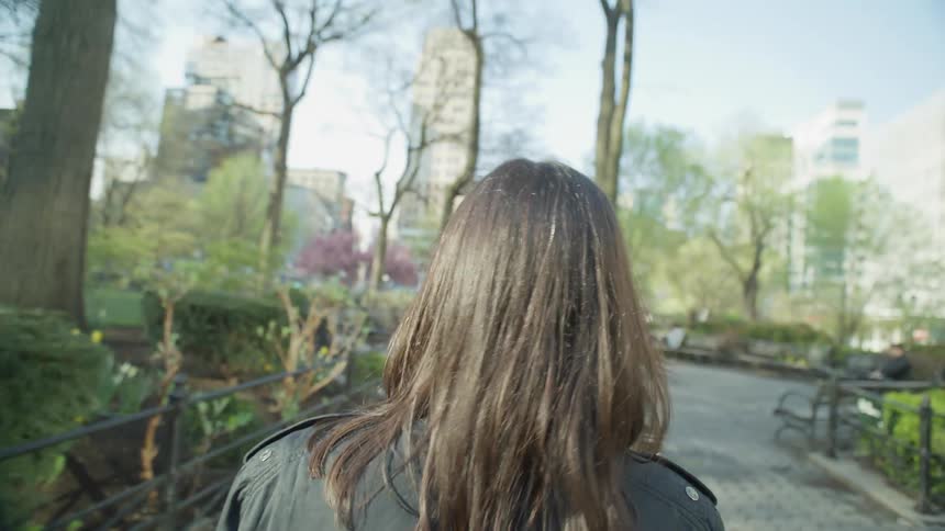 A woman is walking through the park in the city
