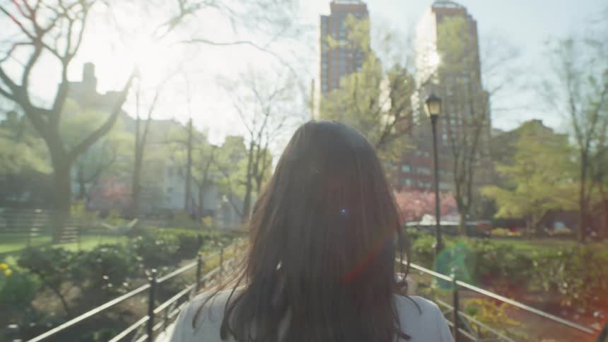 A woman drinks coffee while walking through the park