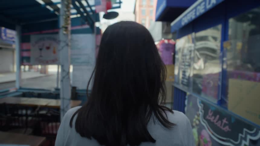 Woman walks past restaurants toward downtown intersection