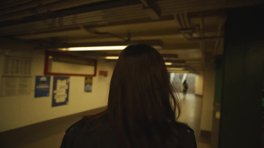Young woman holding a disposable cup of coffee while walking in a subway station