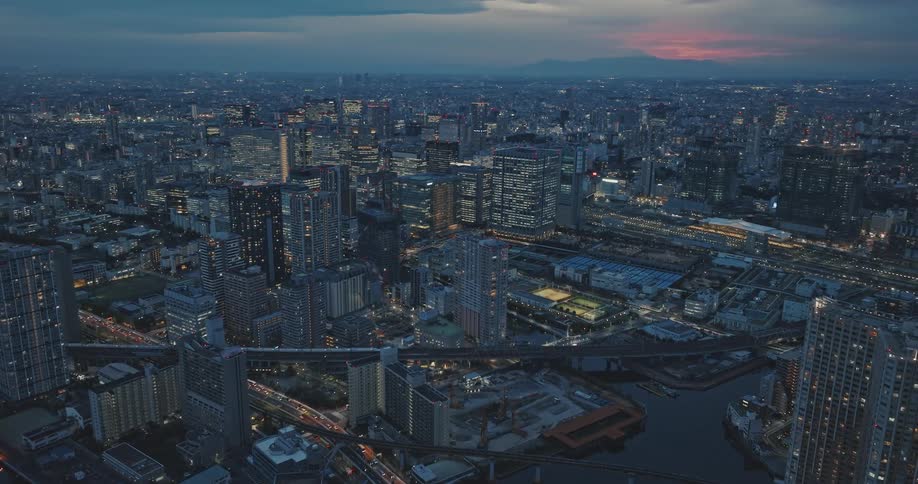 Downtown Tokyo is brightly lit at sunset at trains pass through the city