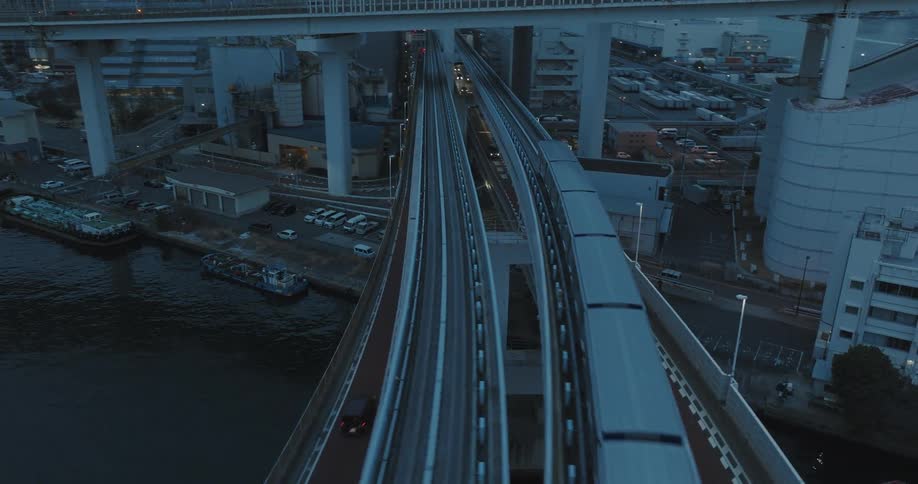 The Tokyo subway train races across the waterfront bridge at blue hour