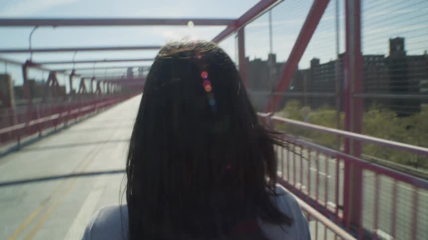 A woman walks across the Williamsburg Bridge in Manhattan New York