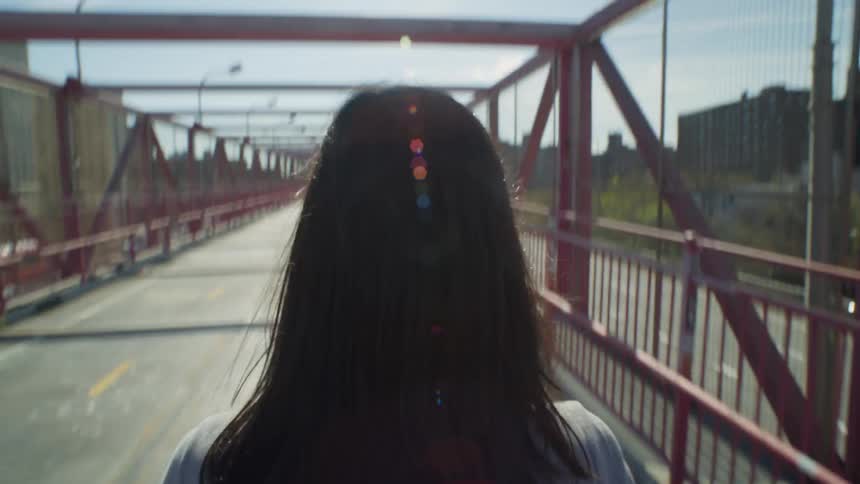 A woman walks on an overpass above a highway