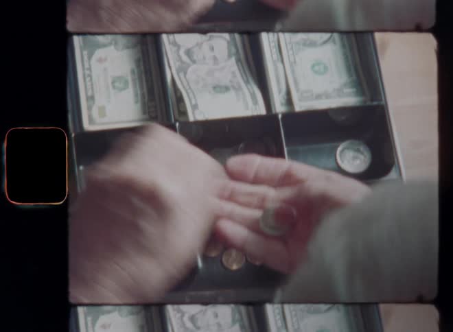 Hands of a person with gray shirt opening old cash register an placing the money that he made from selling a product to a customer in his store or shop into the drawer before closing it on vintage Super-8 film footage