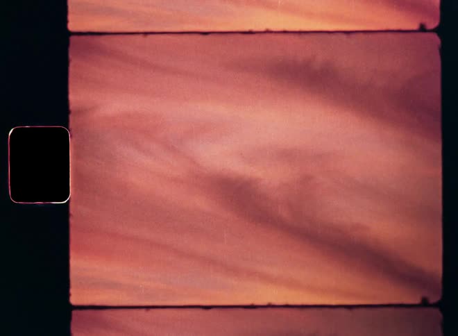 Stratus clouds in an abstract film clip of a pink or red evening sky with vibrant colors as the sun sets and the vibrant evening sky is colored by the afterglow of a beautiful sunset on vintage Super 8mm