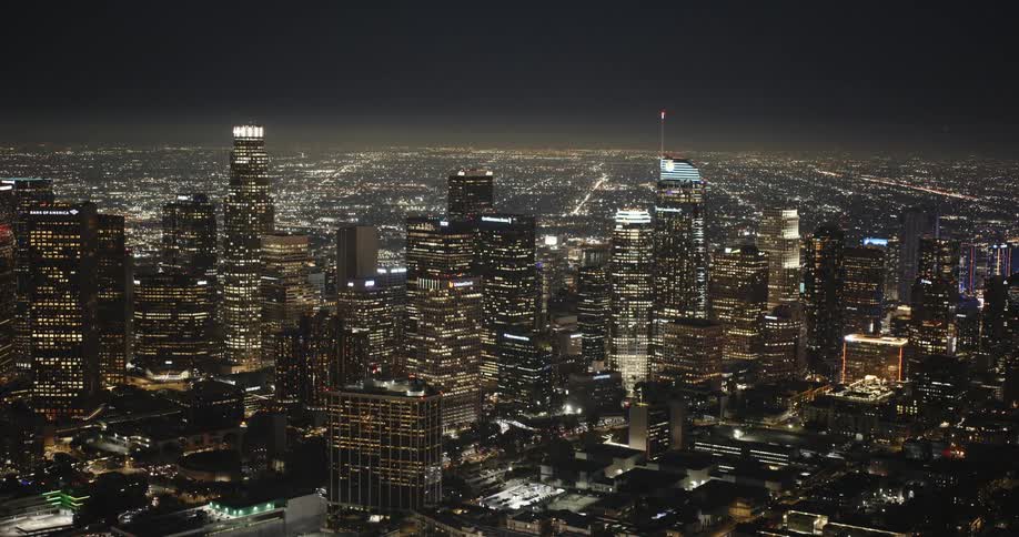 The downtown Los Angeles skyline is brightly lit at night