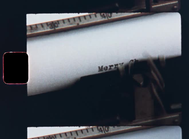 Vintage Super-8 mm close up of an old retro typewriter that taps out Merry Christmas onto a piece of paper wishing great or happy holidays in a x-mas letter or card for the heartwarming holiday season during winter break