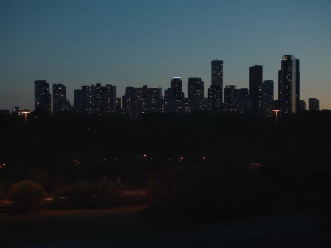 A city center with several tall buildings and lights on at dusk