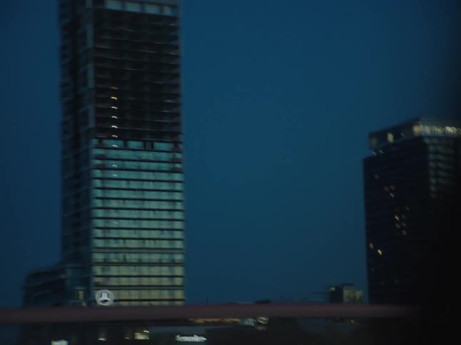 City and skyscrapers at dusk seen from a moving vehicle