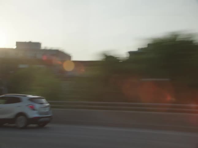 Car drives along highway passing city buildings