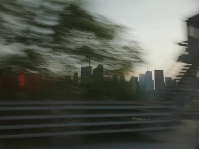 The city skyline unfolds as the vehicle moves through the dusklit streets